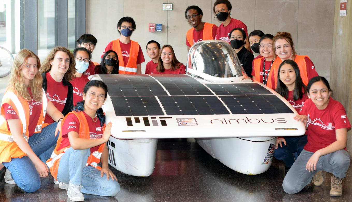 Members of the Solar Electric Vehicle Team posing around their car in Lobby 13