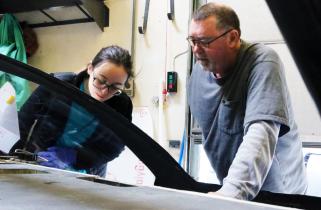 McAtamney leans on car while a student inspects the front suspension.